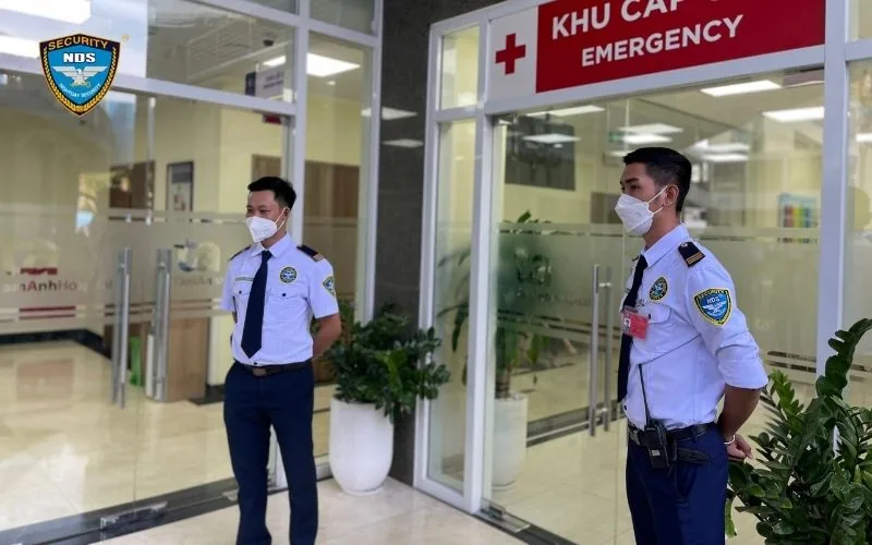 Hai nhân viên bảo vệ Ngày & Đêm đeo khẩu trang trực trước khu cấp cứu phòng khám