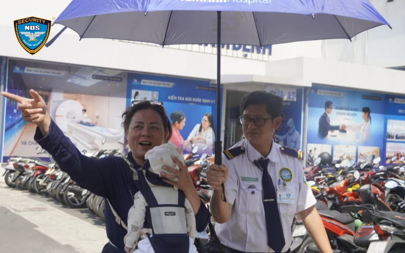 Nhân viên Ngày và Đêm che ô và hướng dẫn khách tại bãi xe