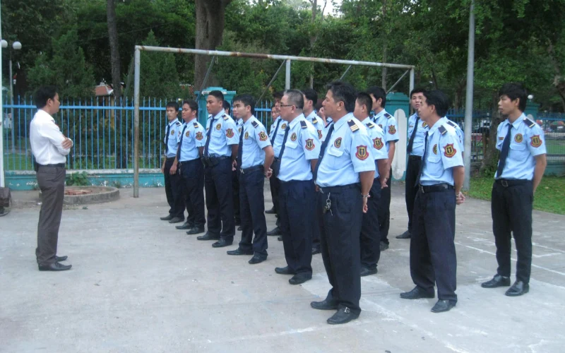 Nhân viên bảo vệ xếp hàng nghe hướng dẫn tại sân ngoài trời